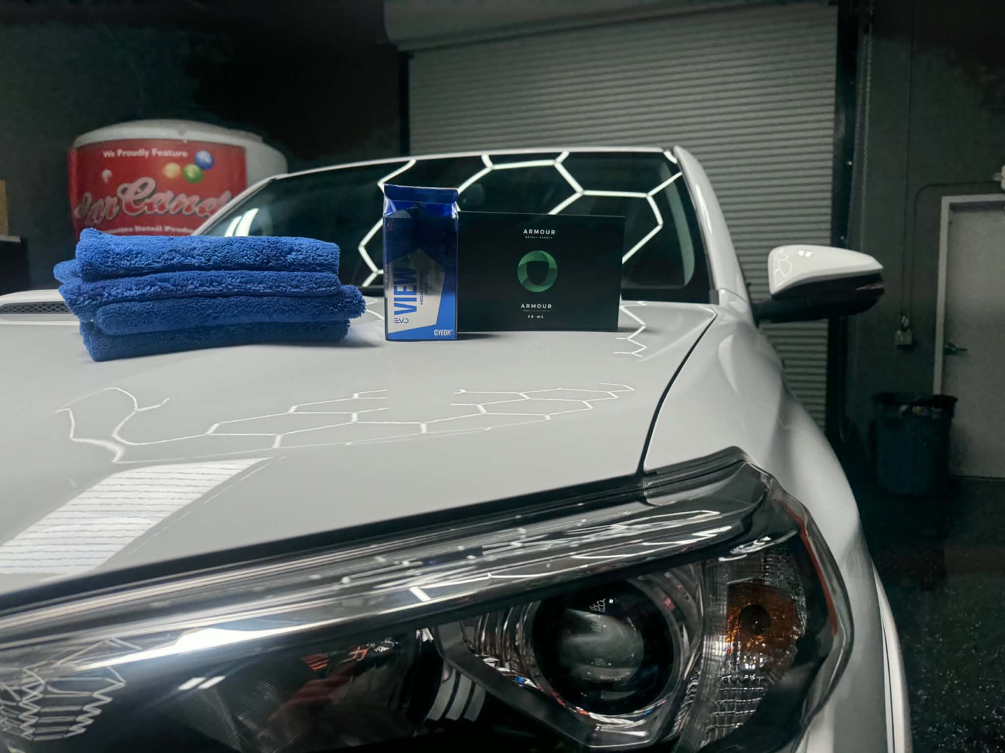Ceramic coating products set out on the mirror-gloss hood of a Toyota 4Runner during its paint correction and ceramic coating job