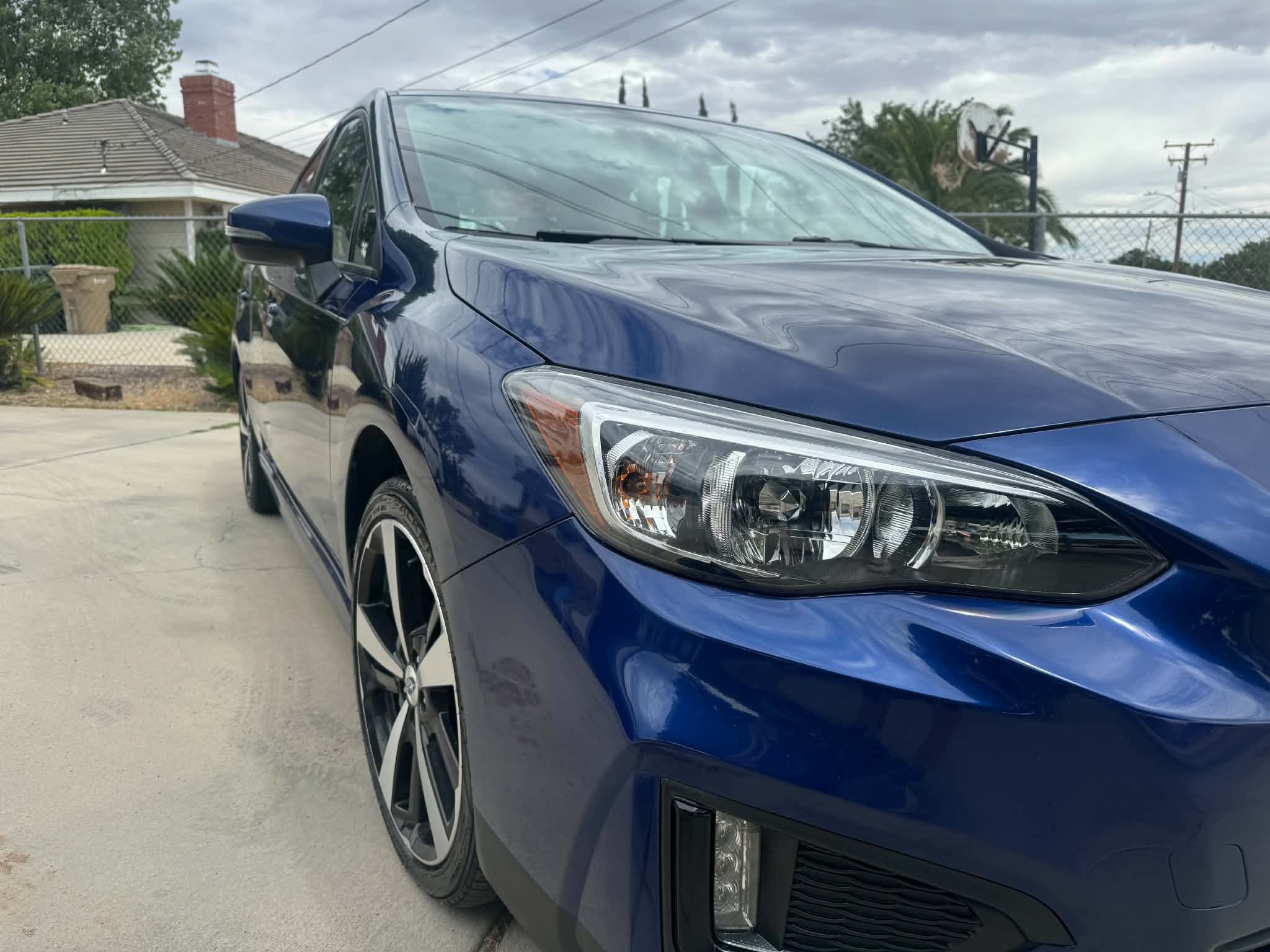 Crystal-clear restored headlight on a blue Subaru after polishing and ceramic sealing